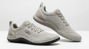 A pair of light grey Xero Shoes featuring mesh uppers, lace closures, and textured rubber soles. Designed for walking, they deliver all-day comfort with ventilation holes and a minimalistic style. The "Xero" brand name is prominently displayed on the shoes.